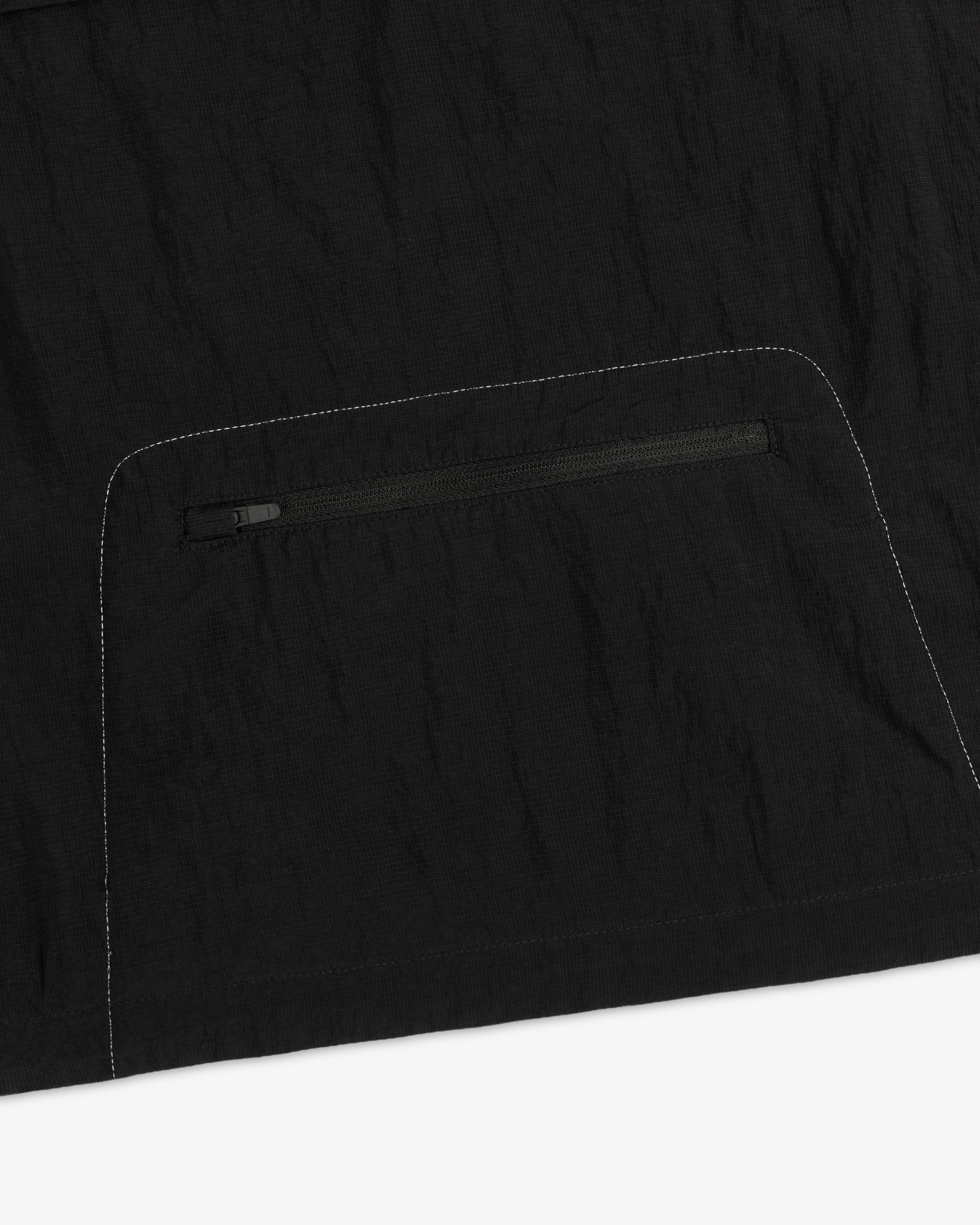 Close-up of the ALD / New Balance Breathable Half-Zip Pullover in black with a zip pocket and white stitching.