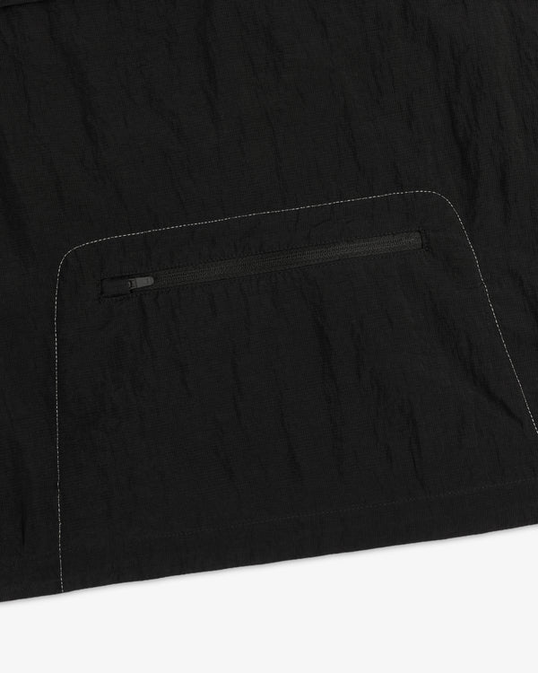 Close-up of the ALD / New Balance Breathable Half-Zip Pullover in black with a zip pocket and white stitching.