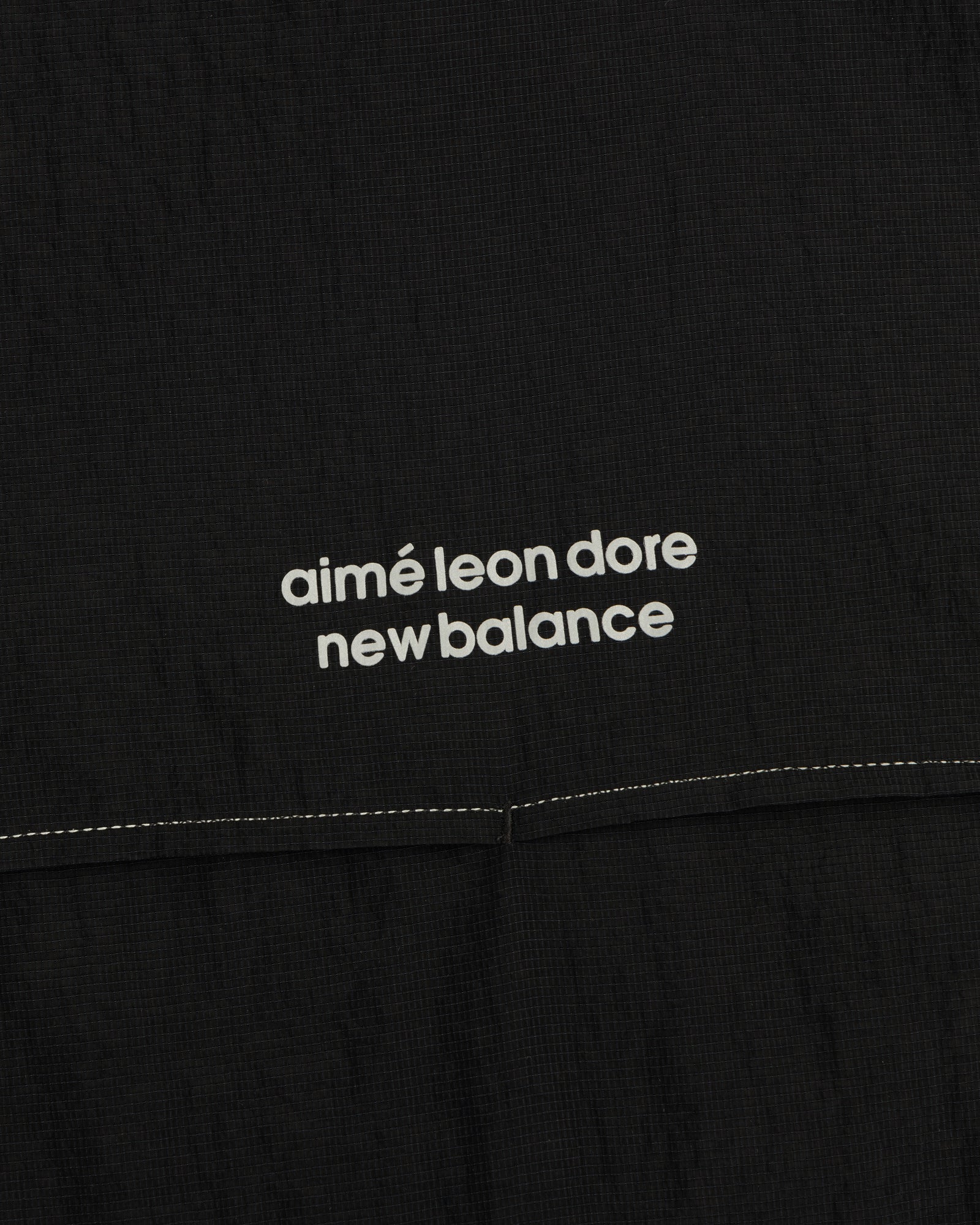 Black ALD / New Balance Breathable Half-Zip Pullover with white logo text and a visible stitched seam below.