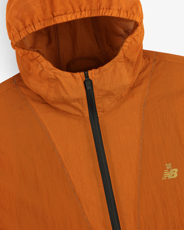 Close-up of the orange ALD / New Balance Breathable Half-Zip Pullover with black zipper and chest logo.