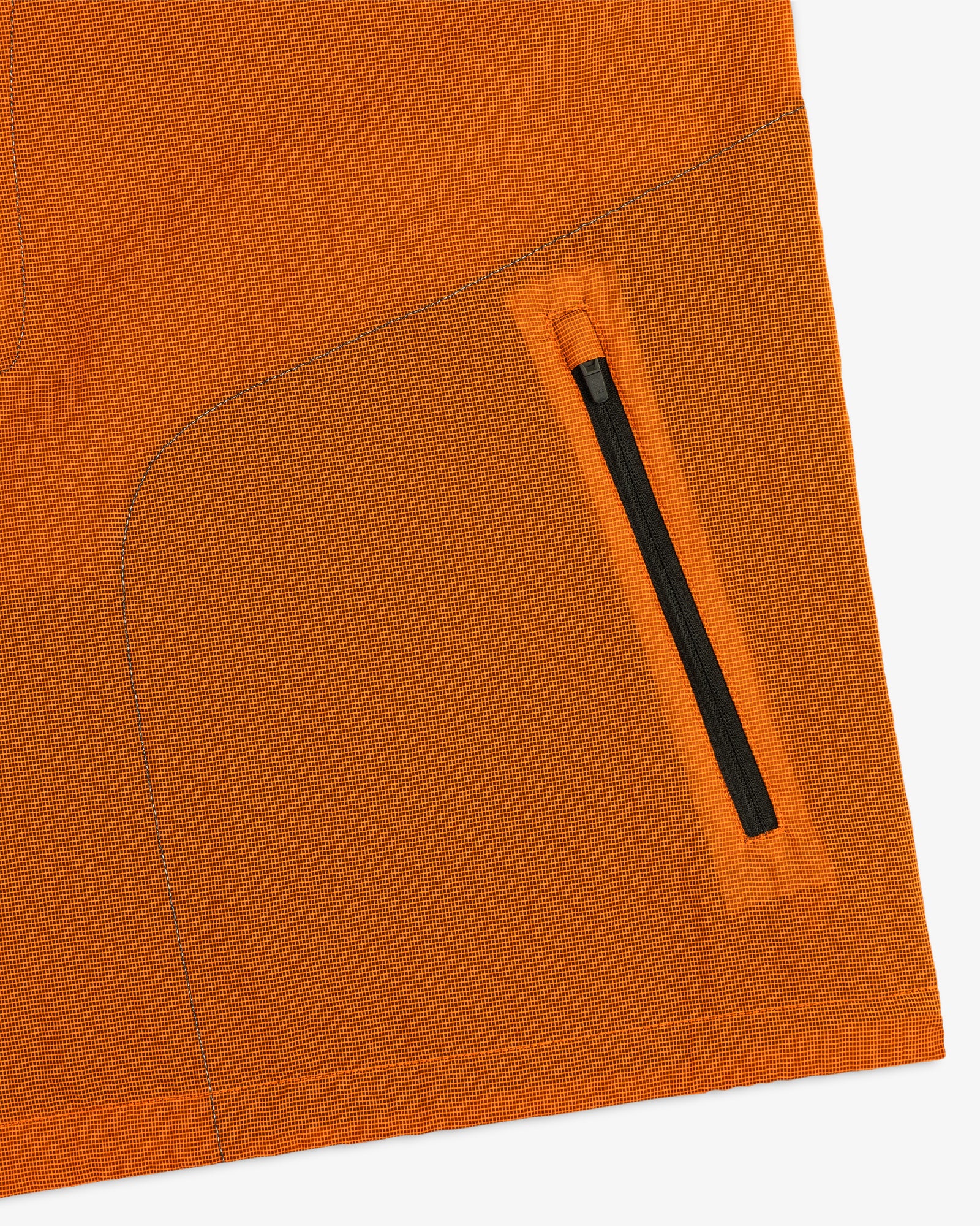 Close-up of the ALD / New Balance Breathable Half-Zip Pullover in orange, featuring a diagonal black zipper pocket.