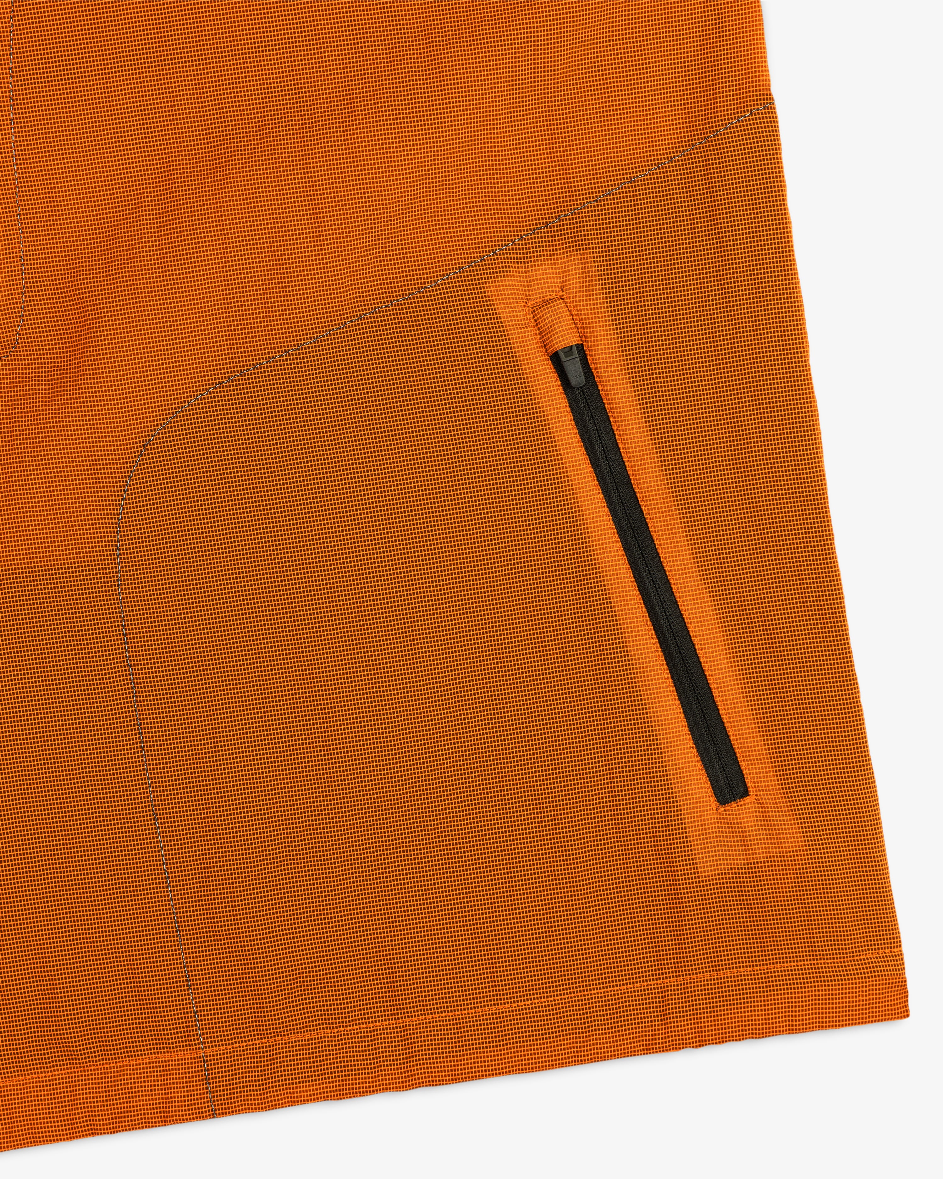 Close-up of the ALD / New Balance Breathable Half-Zip Pullover in orange, featuring a diagonal black zipper pocket.