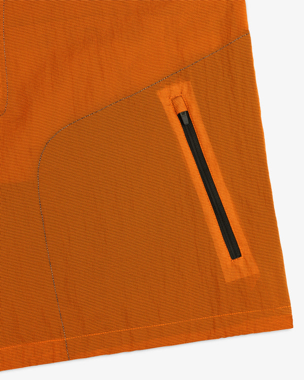 Close-up of the ALD / New Balance Breathable Half-Zip Pullover in orange, featuring a diagonal black zipper pocket.