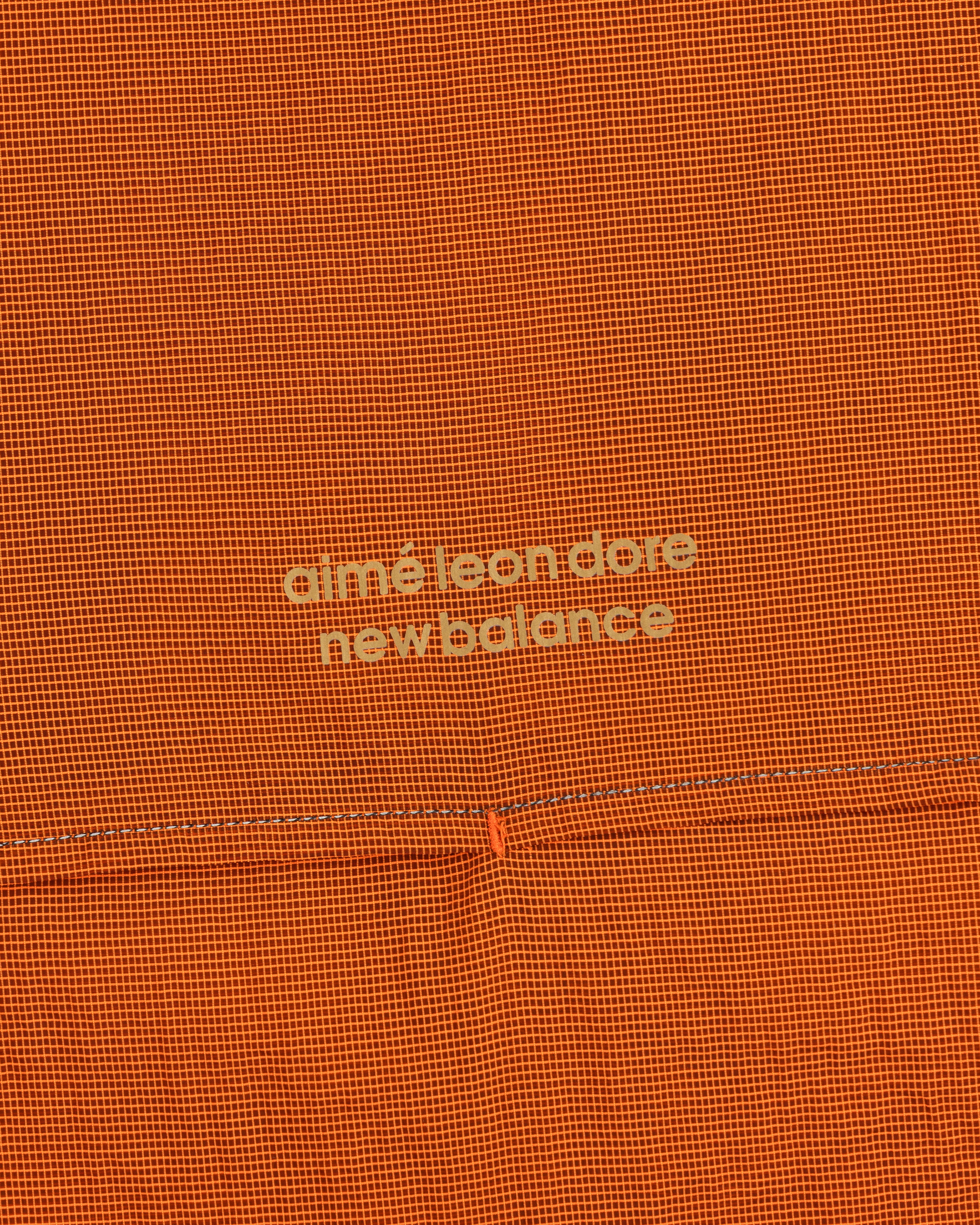 Orange textured ALD / New Balance Breathable Half-Zip Pullover with light yellow logo at the center.