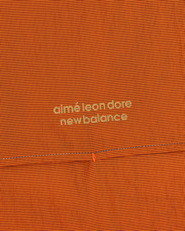 Orange textured ALD / New Balance Breathable Half-Zip Pullover with light yellow logo at the center.