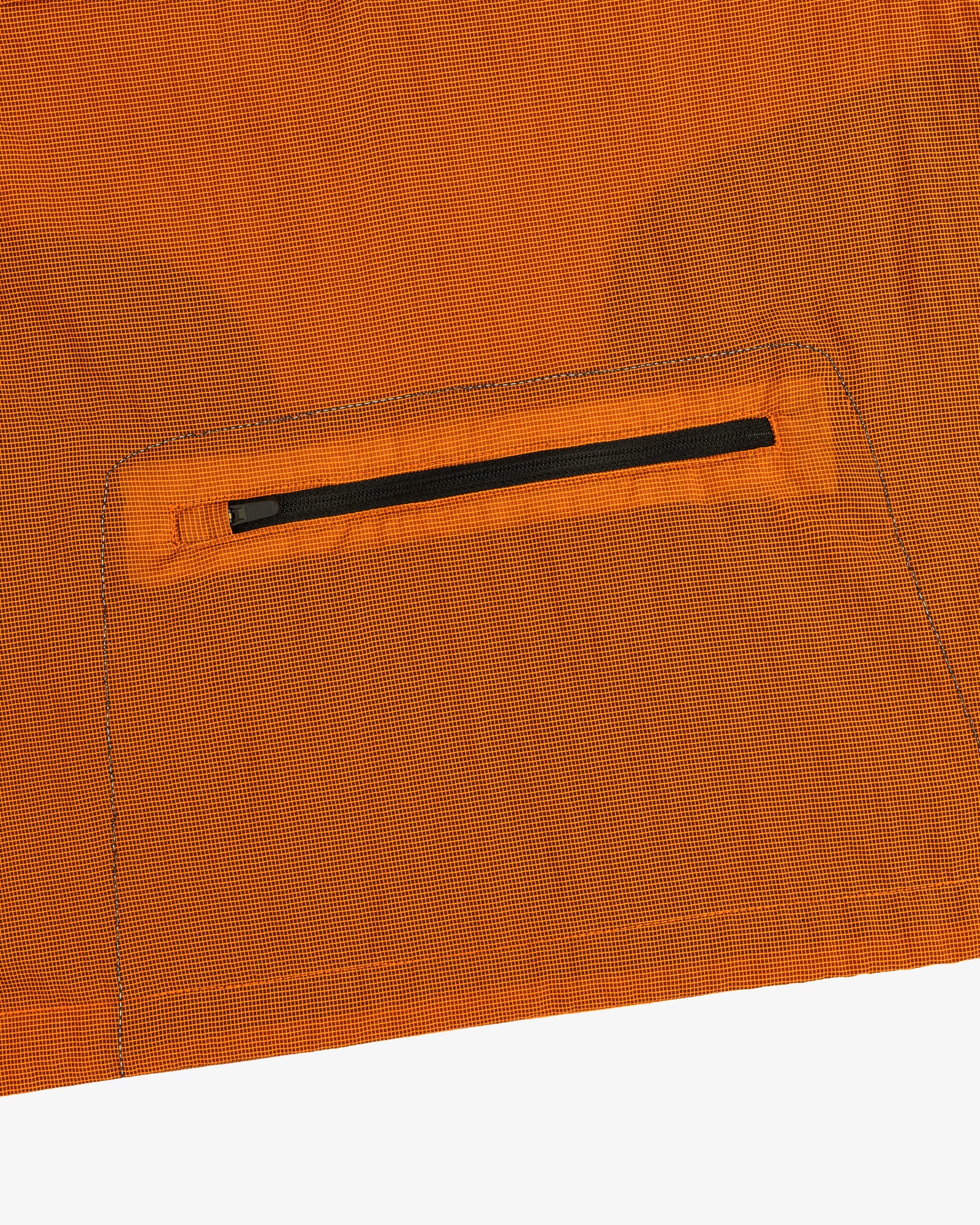 Close-up of the ALD / New Balance Breathable Half-Zip Pullover’s orange ripstop fabric with a black zip pocket.
