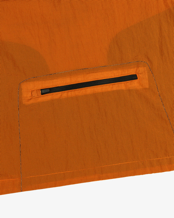 Close-up of the ALD / New Balance Breathable Half-Zip Pullover’s orange ripstop fabric with a black zip pocket.