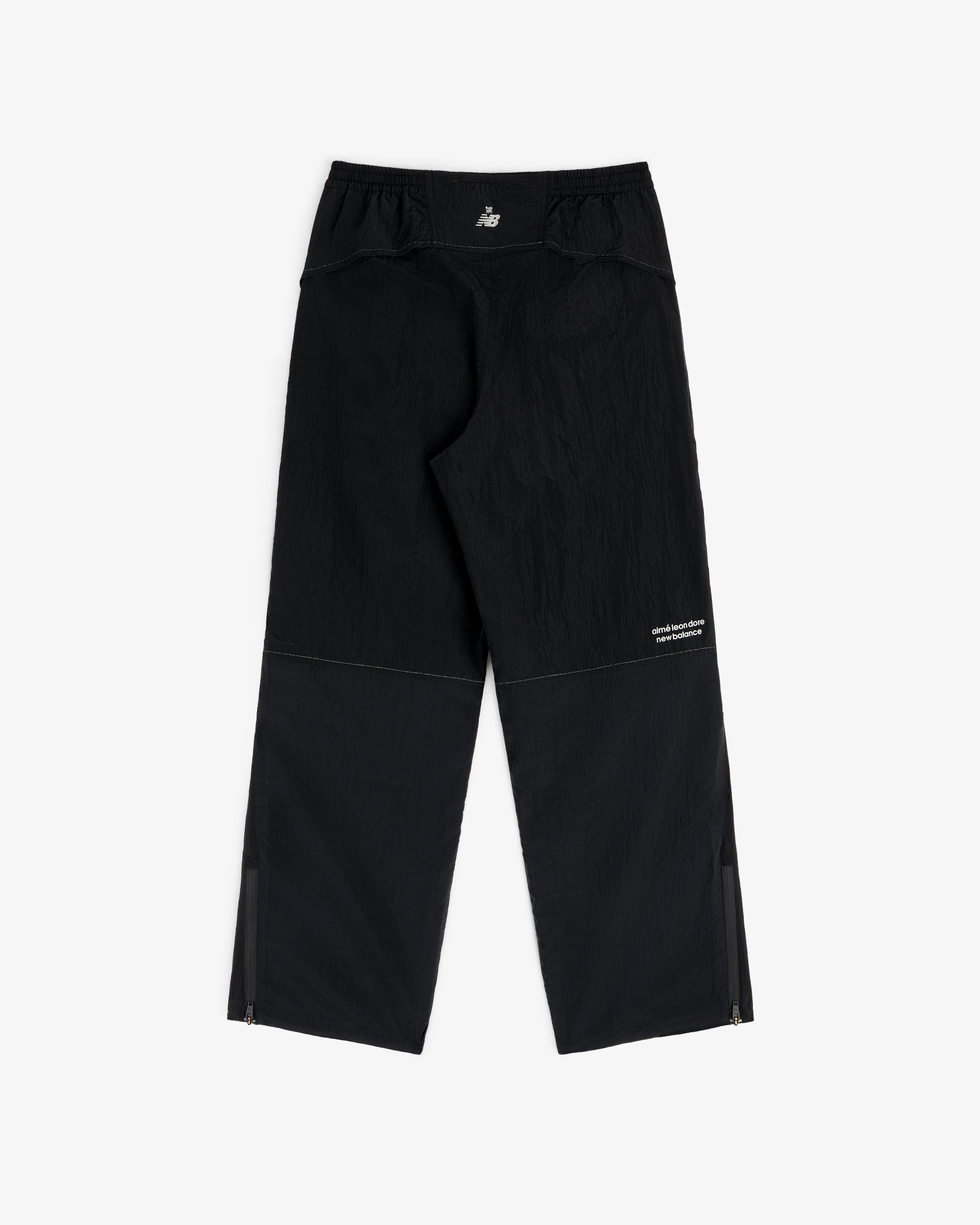 ALD / New Balance Lightweight Nylon Warmup Pant in black with subtle texture, white logo, and zippered ankles.