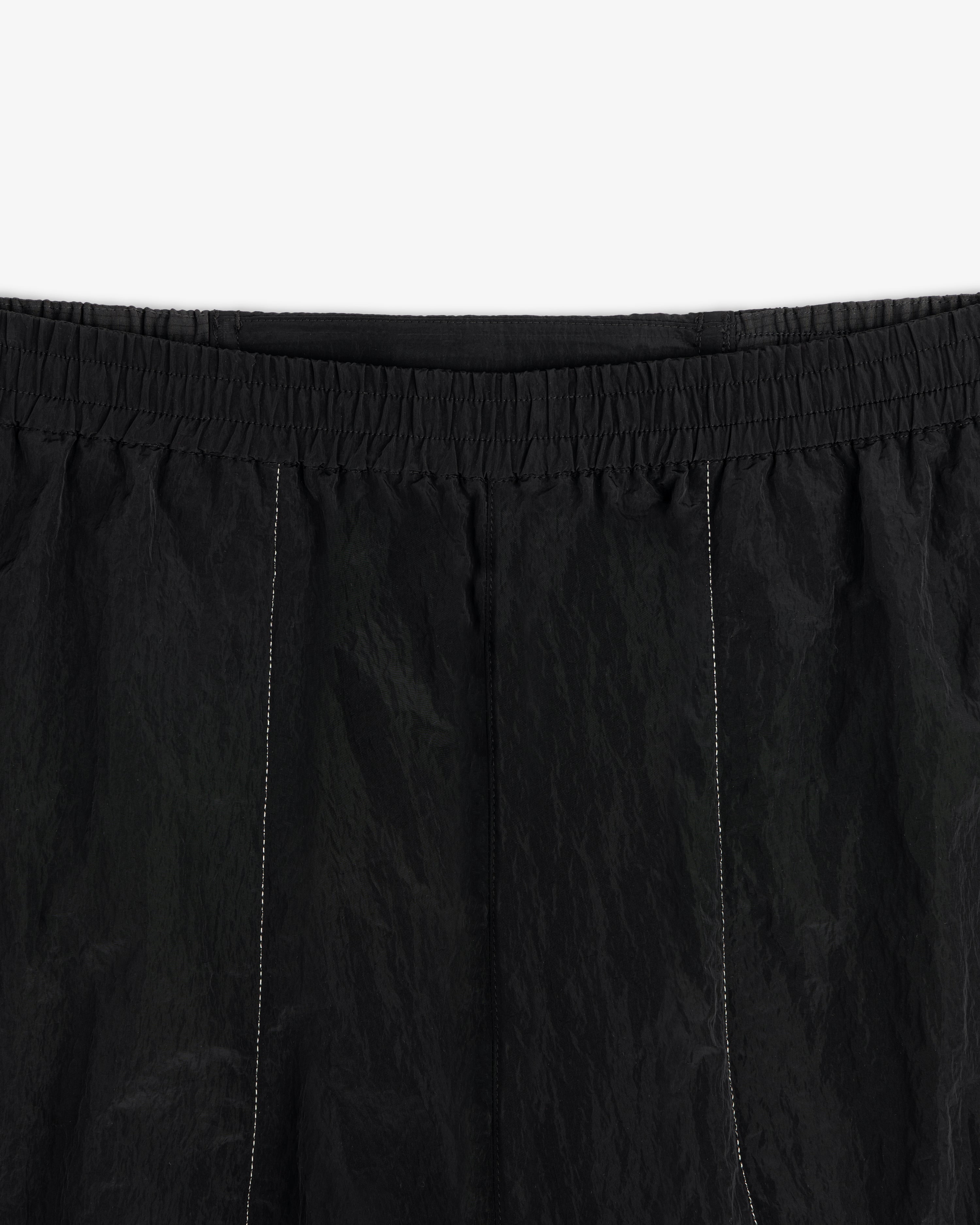 Close-up of ALD / New Balance Lightweight Nylon Warmup Pant in black with elastic waistband and white stitching.