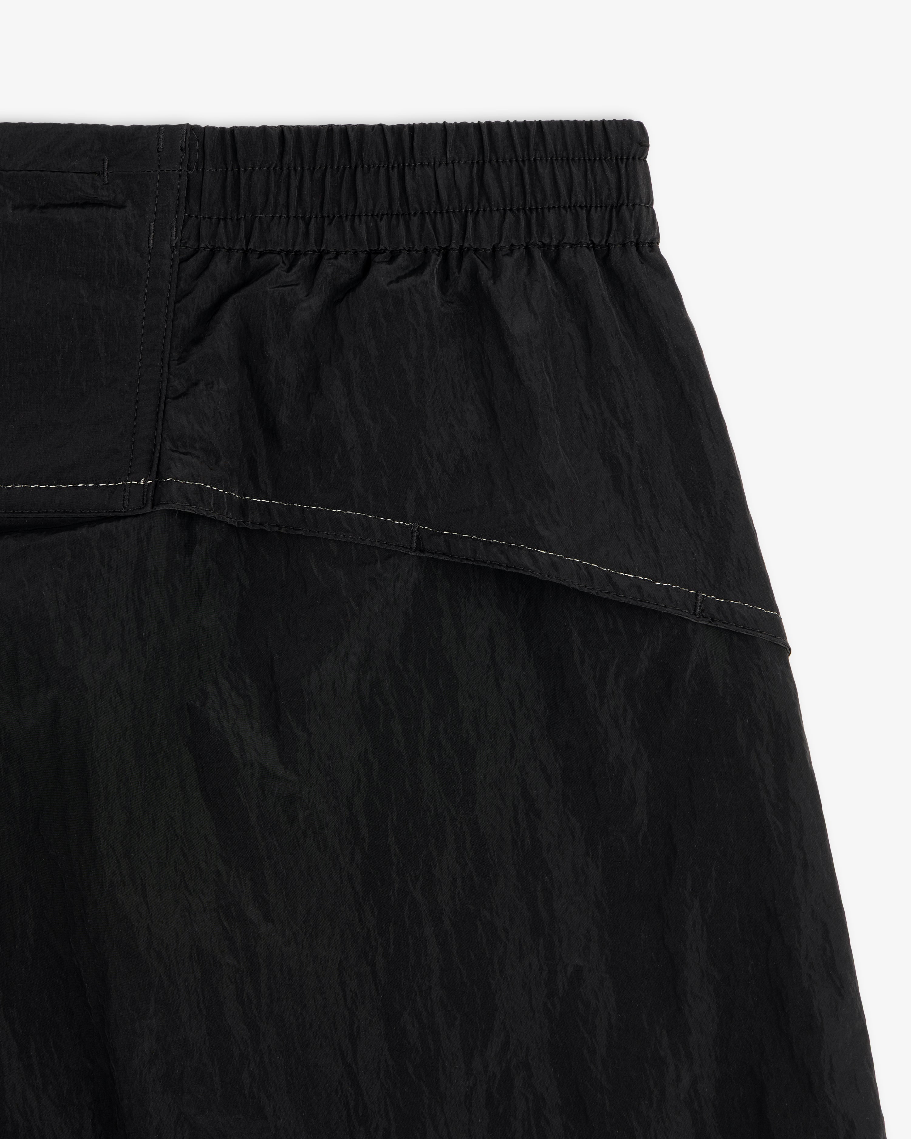 Close-up of ALD / New Balance Lightweight Nylon Warmup Pant in black with elastic waistband and white stitching.