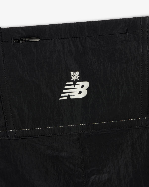 Close-up of black ALD / New Balance Lightweight Nylon Warmup Pant with a white logo and snowflake symbol above it.