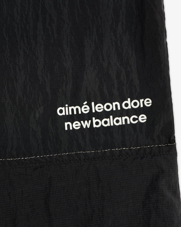 Close-up of black ALD / New Balance Lightweight Nylon Warmup Pant with white text printed near the seam.