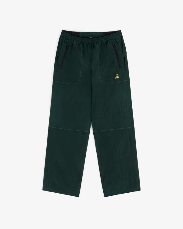 ALD / New Balance Lightweight Nylon Warmup Pant in dark green with front pockets, black zippers, and yellow logo.