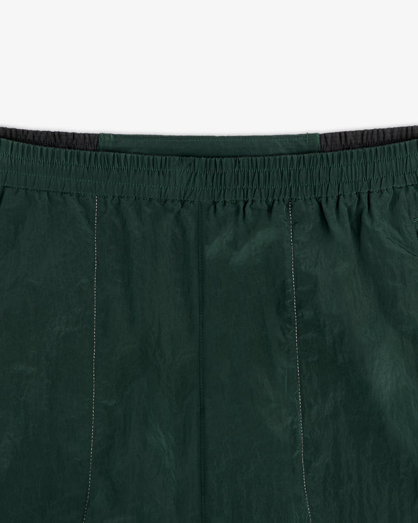 Close-up of ALD / New Balance Lightweight Nylon Warmup Pant in dark green with elastic waistband and stitching details.