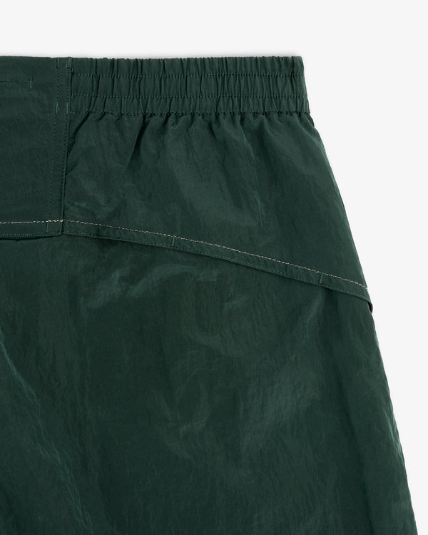 Close-up of the waistband and upper fabric of ALD / New Balance Lightweight Nylon Warmup Pant in dark green.