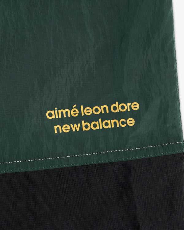 Close-up of green and black ALD / New Balance Lightweight Nylon Warmup Pant with yellow printed text.
