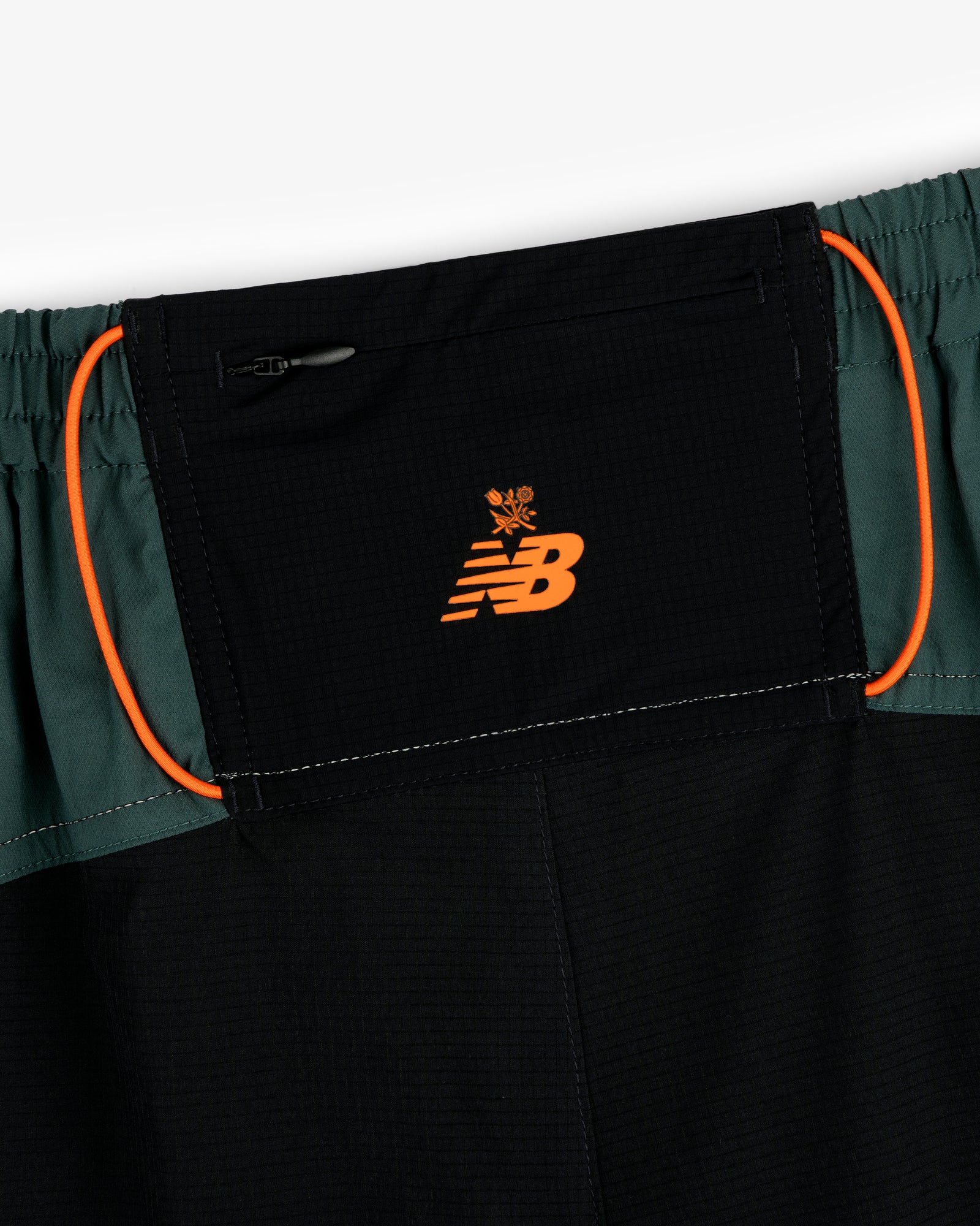 Close-up of ALD / New Balance Performance Lightweight Running Short in black with orange logo and green side panels.