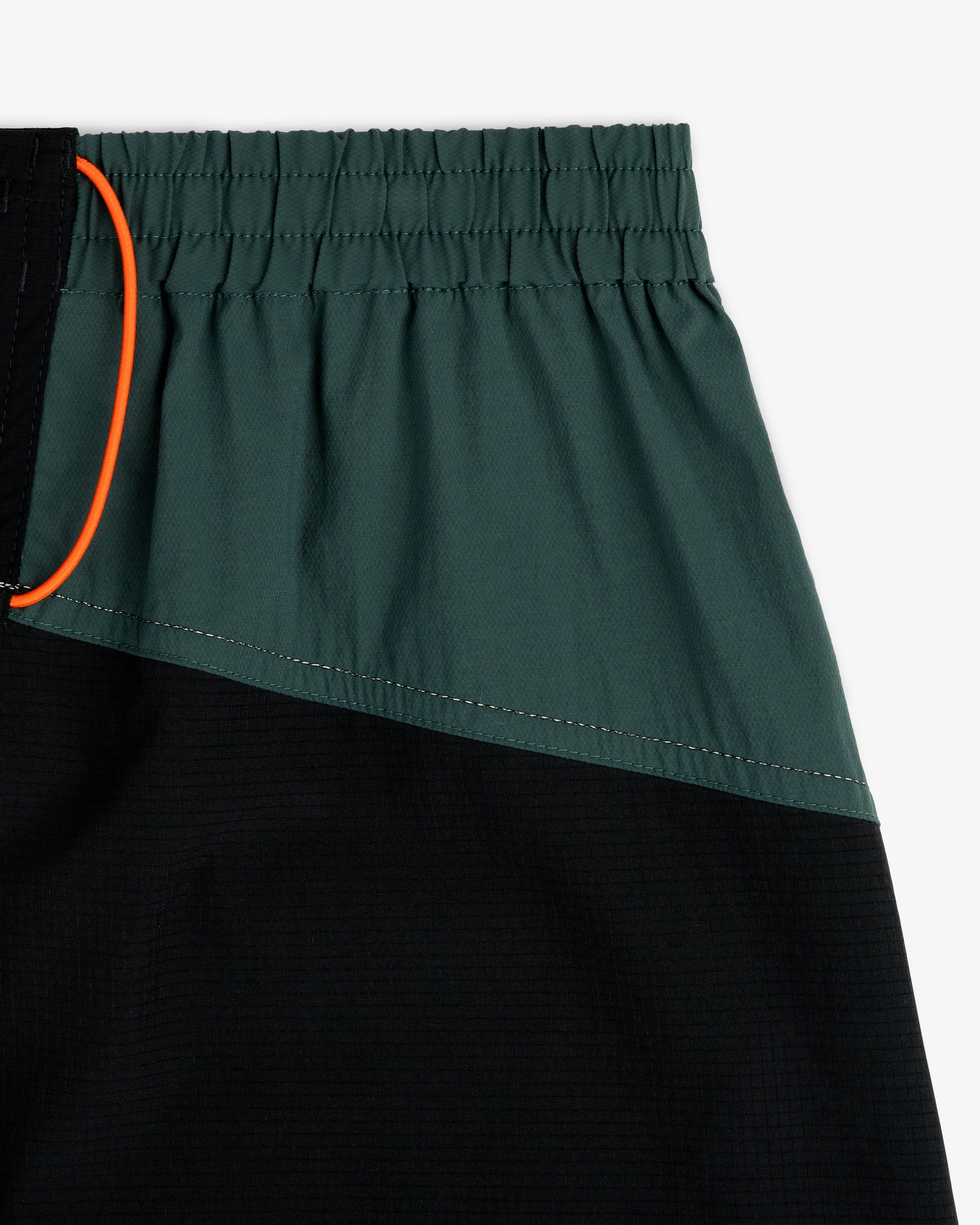 Close-up of ALD / New Balance Performance Lightweight Running Short with dark green, black panels, and orange drawstring.