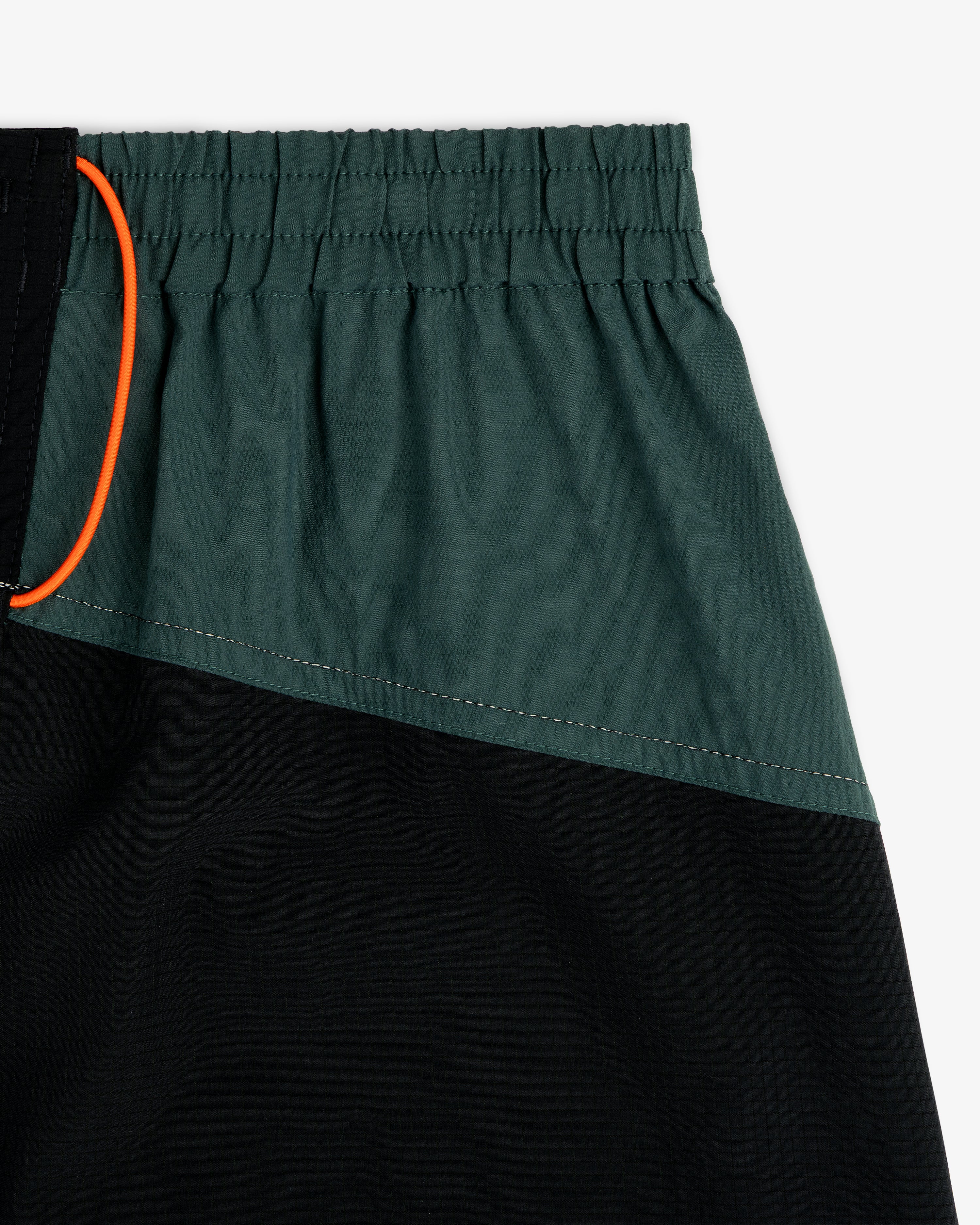 Close-up of ALD / New Balance Performance Lightweight Running Short with dark green, black panels, and orange drawstring.