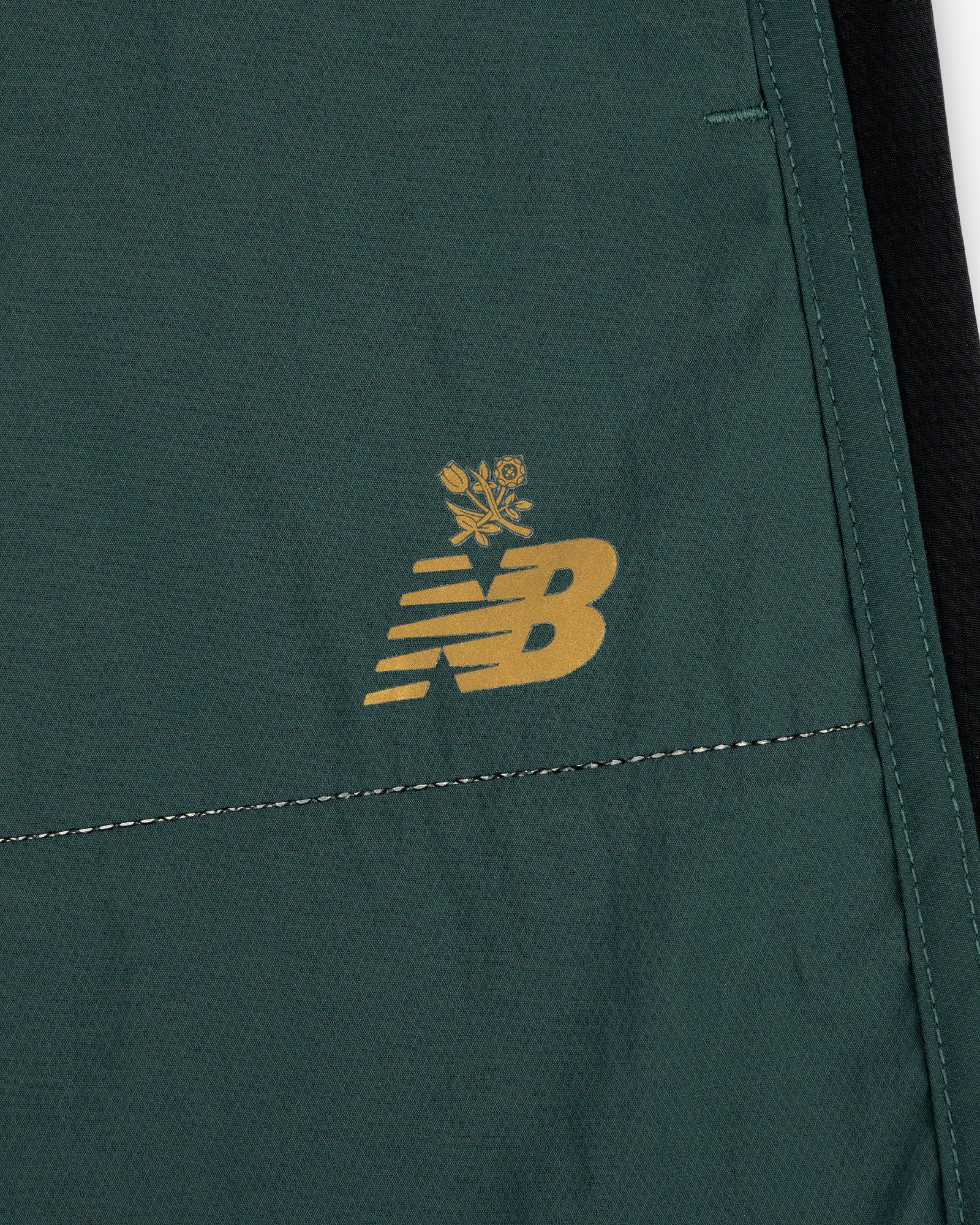 Close-up of green ALD / New Balance Performance Lightweight Running Short with yellow logo and floral graphic.