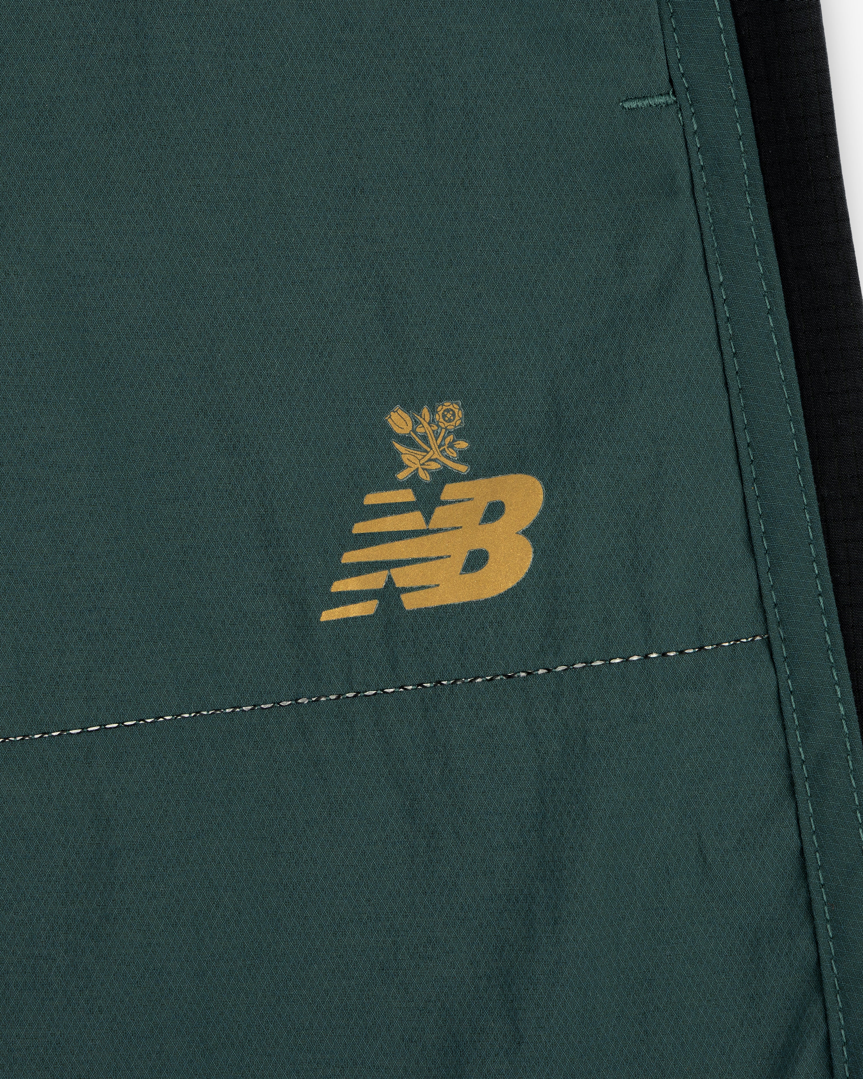 Close-up of green ALD / New Balance Performance Lightweight Running Short with yellow logo and floral graphic.