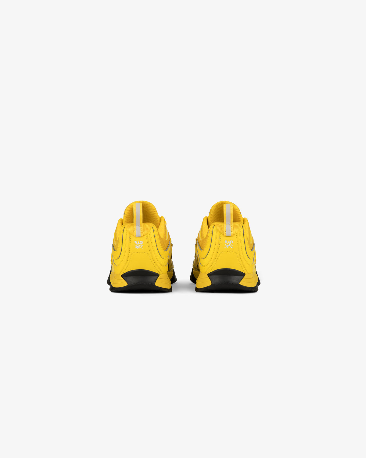 A pair of ALD / New Balance RC56 yellow sneakers seen from the back on a plain white background.
