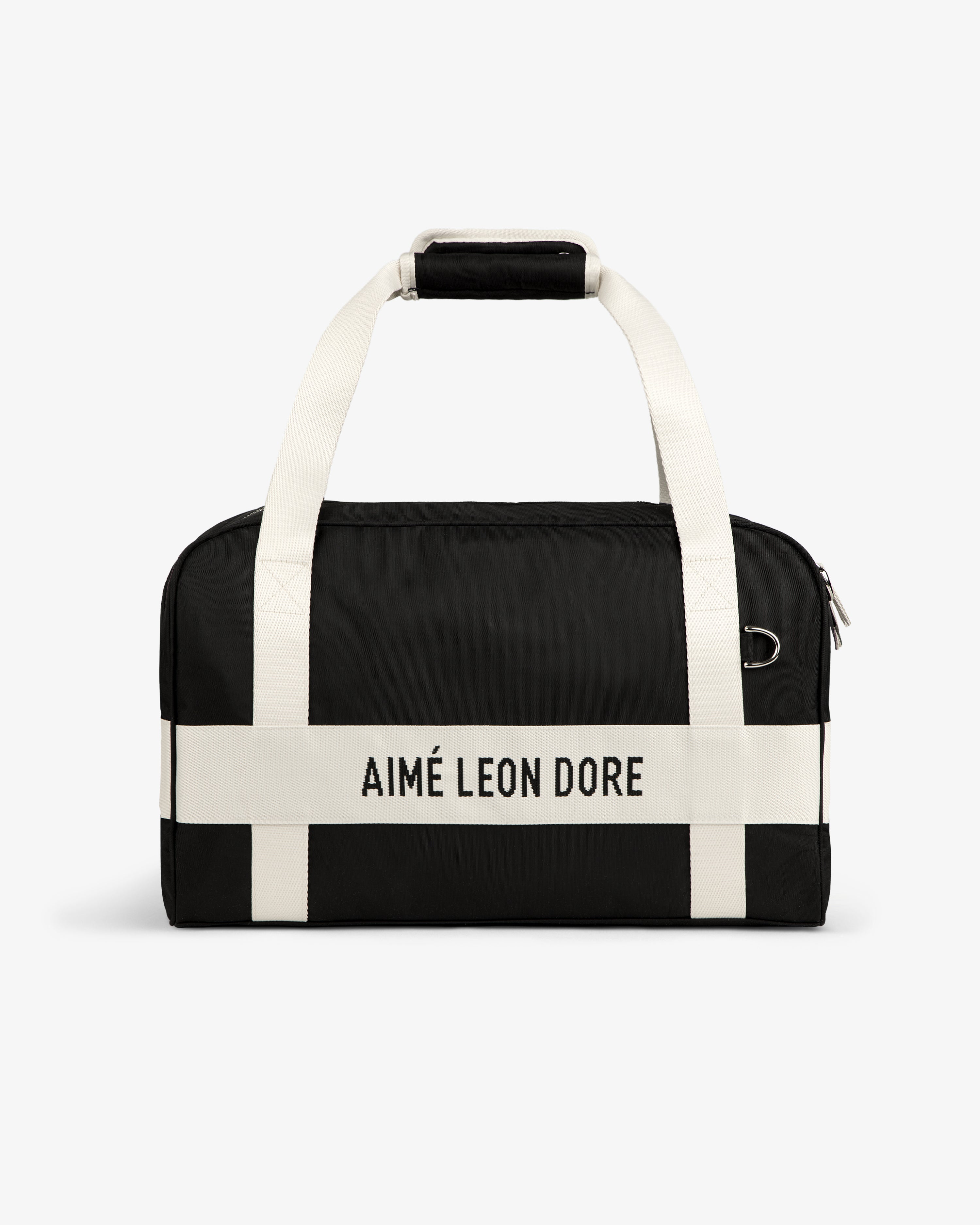 Nylon Duffle Bag in black with white handles and AIMÉ LEON DORE printed on a white front strap.