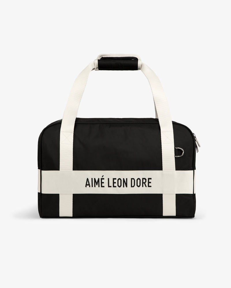 Nylon Duffle Bag in black with white handles and AIMÉ LEON DORE printed on a white front strap.