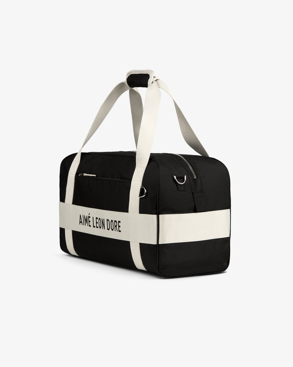 Black and white Nylon Duffle Bag with AIMÉ LEON DORE on the side and white straps, shown on a white background.