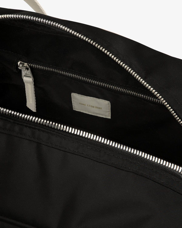 Close-up of an open Nylon Duffle Bag in black with a silver zipper, inside pocket, and white label.