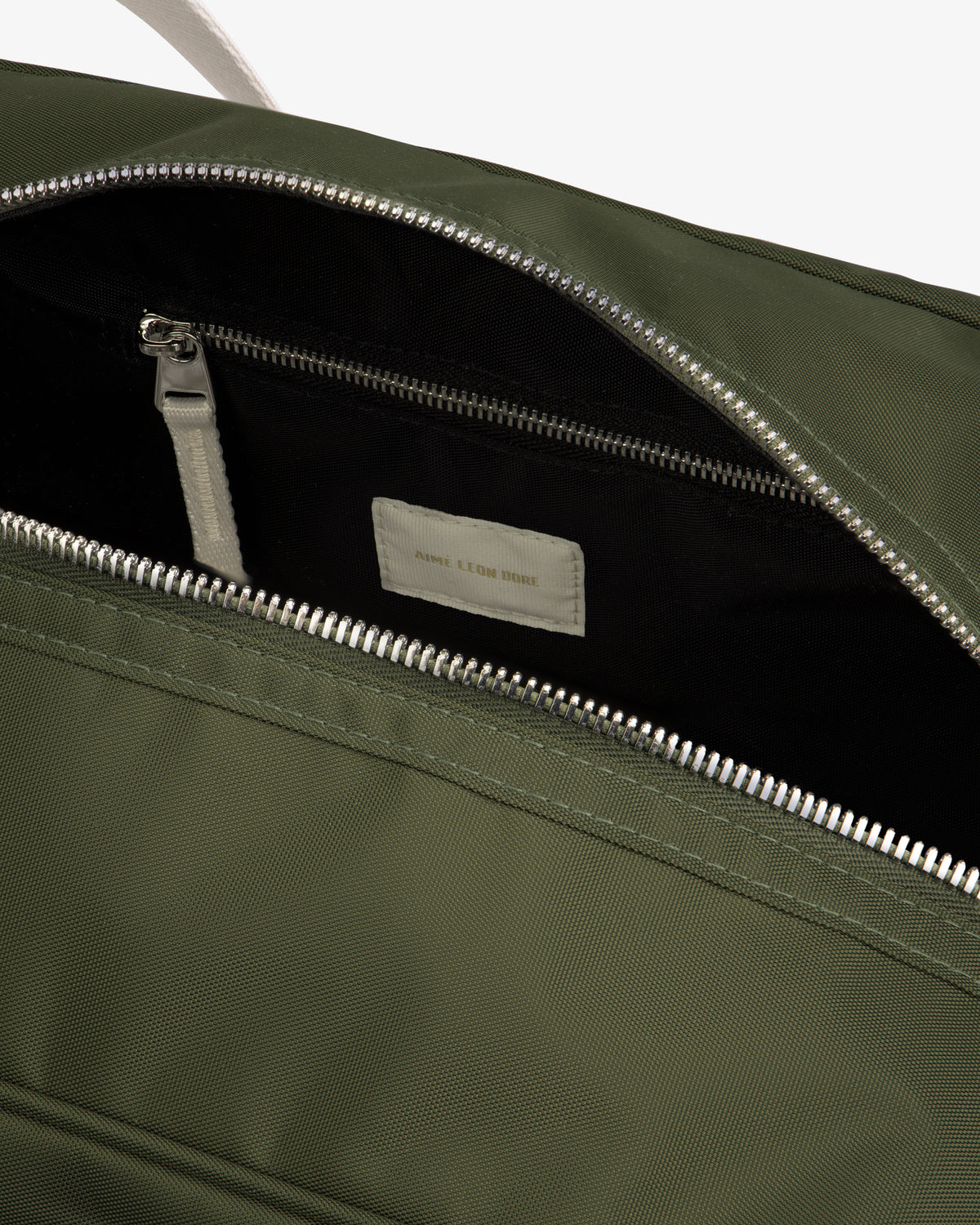 Open green Nylon Duffle Bag showing black zippered interior pocket and a white label inside.