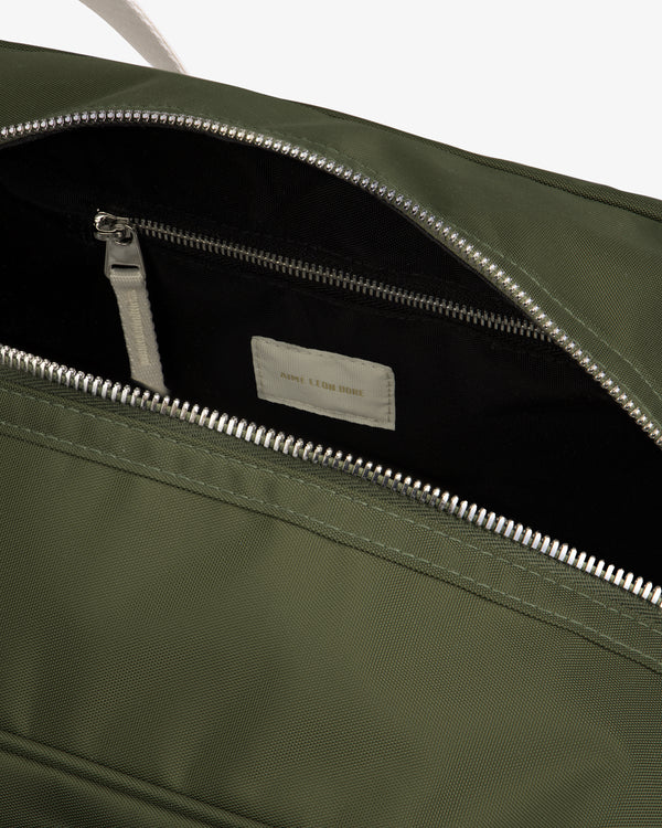 Open green Nylon Duffle Bag showing black zippered interior pocket and a white label inside.