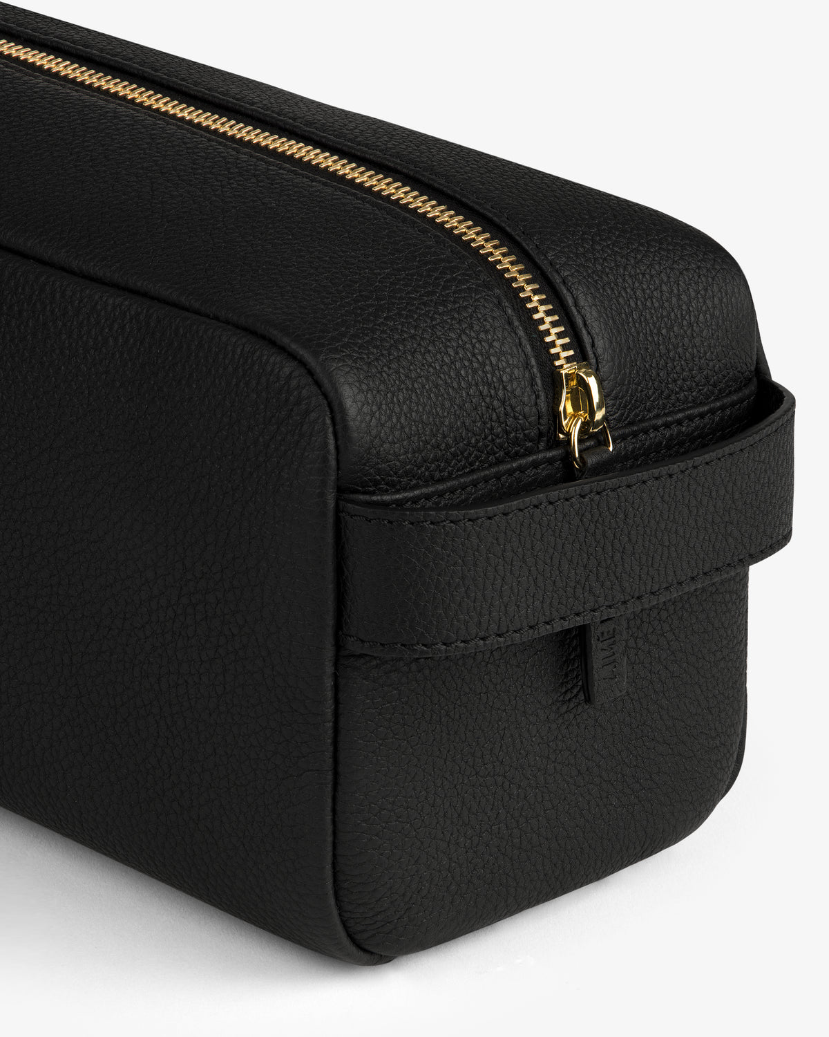 Close-up of the Leather Traveler Kit: a black leather toiletry bag with gold zipper and side handle on white background.