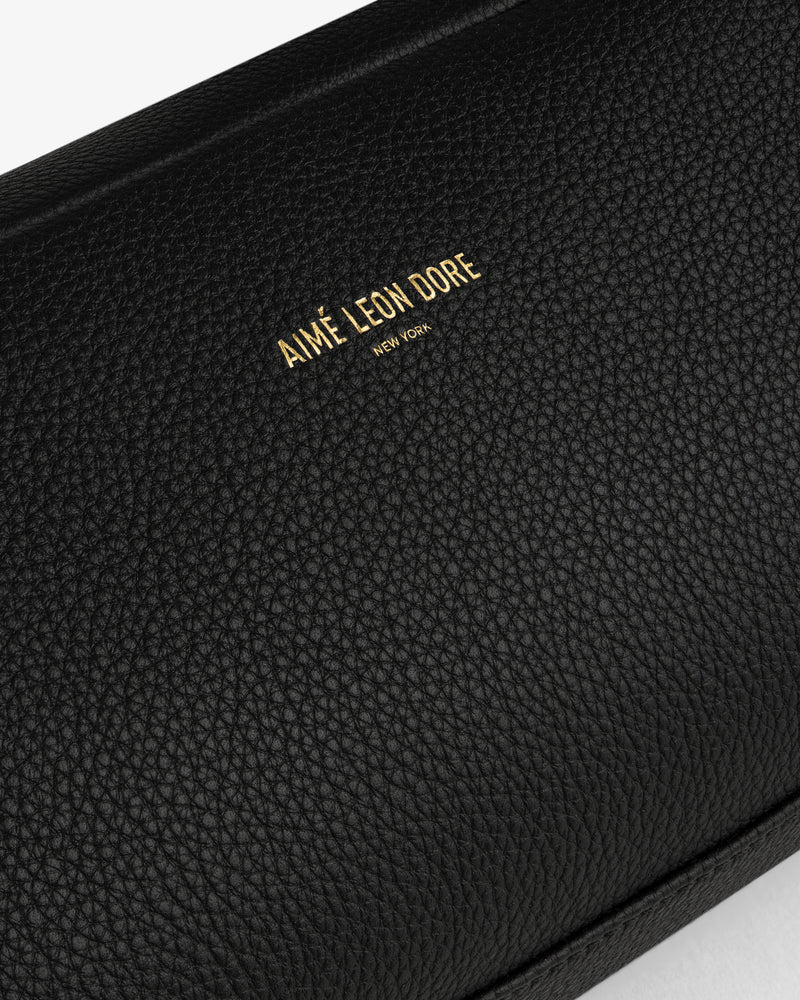 Close-up of the Leather Traveler Kit in black textured leather with gold AIMÉ LEON DORE NEW YORK embossing.