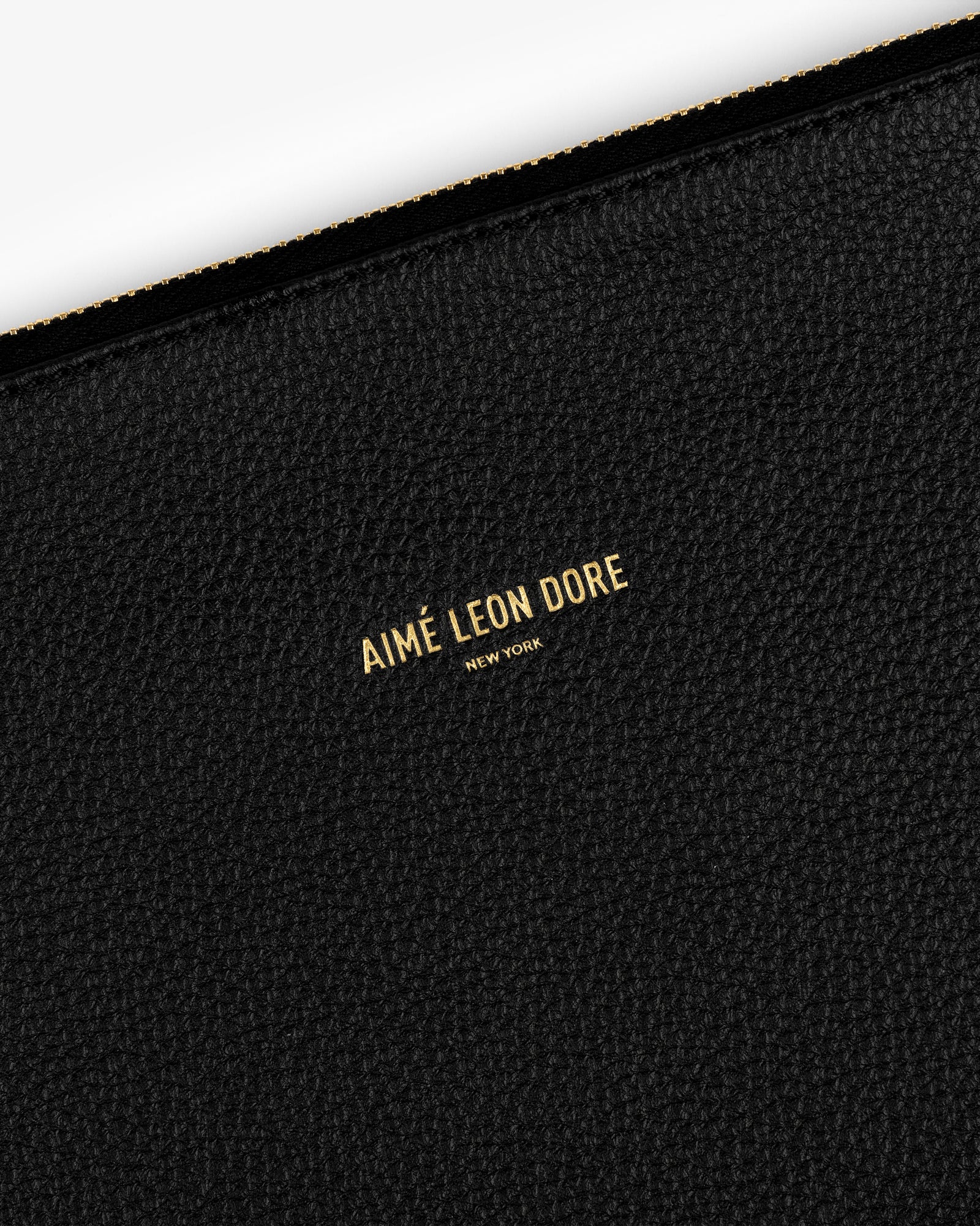 Black textured leather Small Leather Pouch with AIMÉ LEON DORE NEW YORK stamped in small gold letters at the center.
