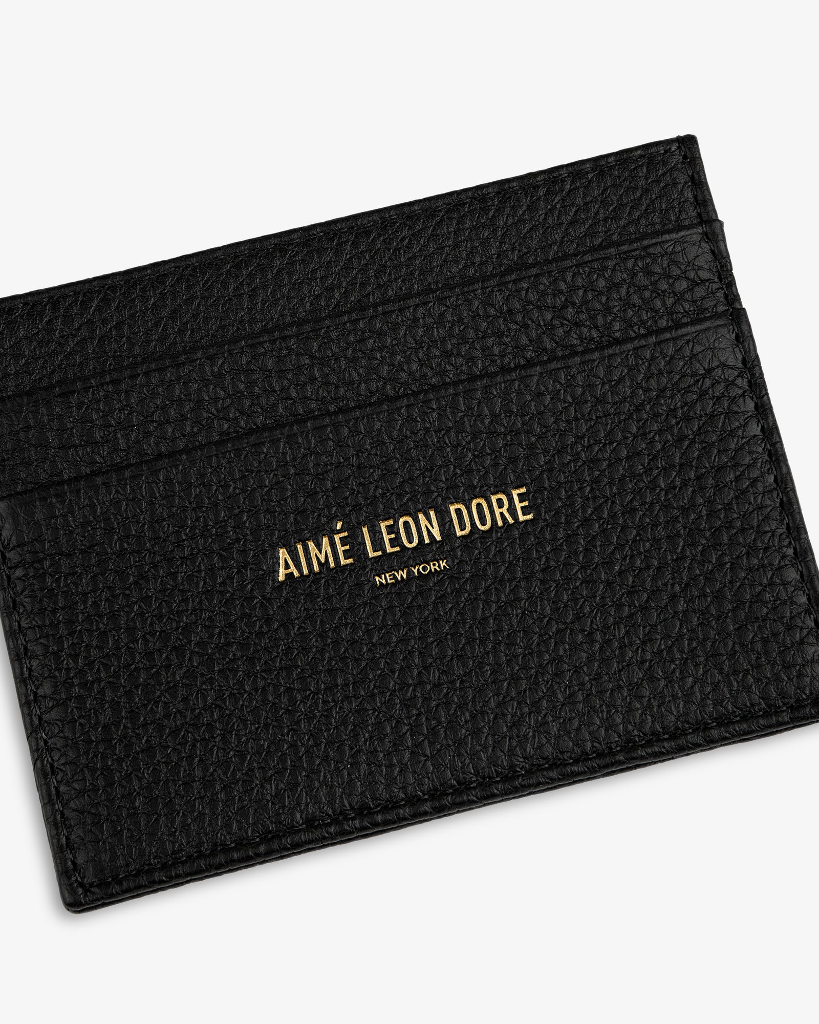 Leather Card Holder in black textured leather with AIMÉ LEON DORE NEW YORK gold lettering on the front.