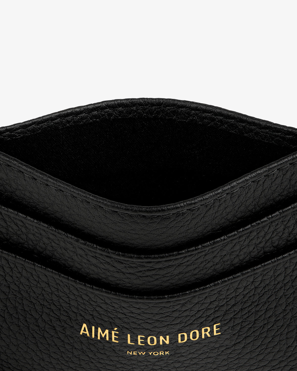 Close-up of the Leather Card Holder in black textured leather with gold AIMÉ LEON DORE NEW YORK lettering.