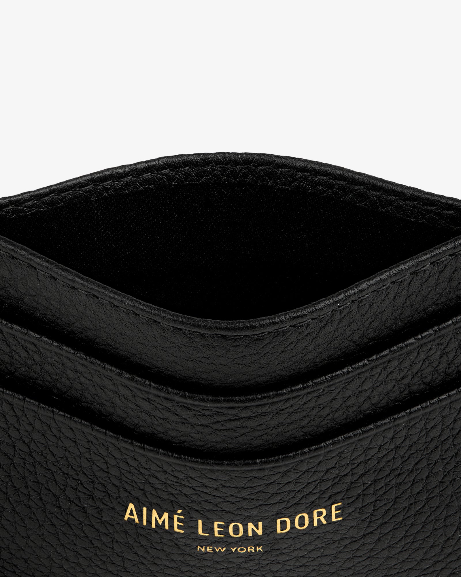 Close-up of the Leather Card Holder in black textured leather with gold AIMÉ LEON DORE NEW YORK lettering.