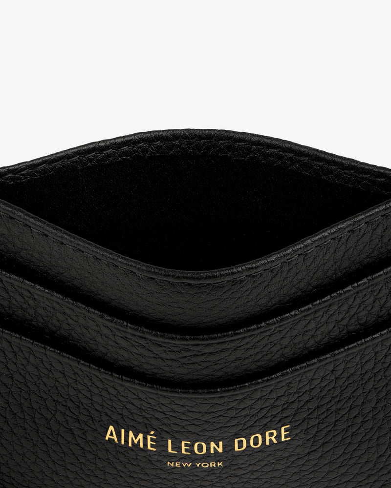 Close-up of the Leather Card Holder in black textured leather with gold AIMÉ LEON DORE NEW YORK lettering.