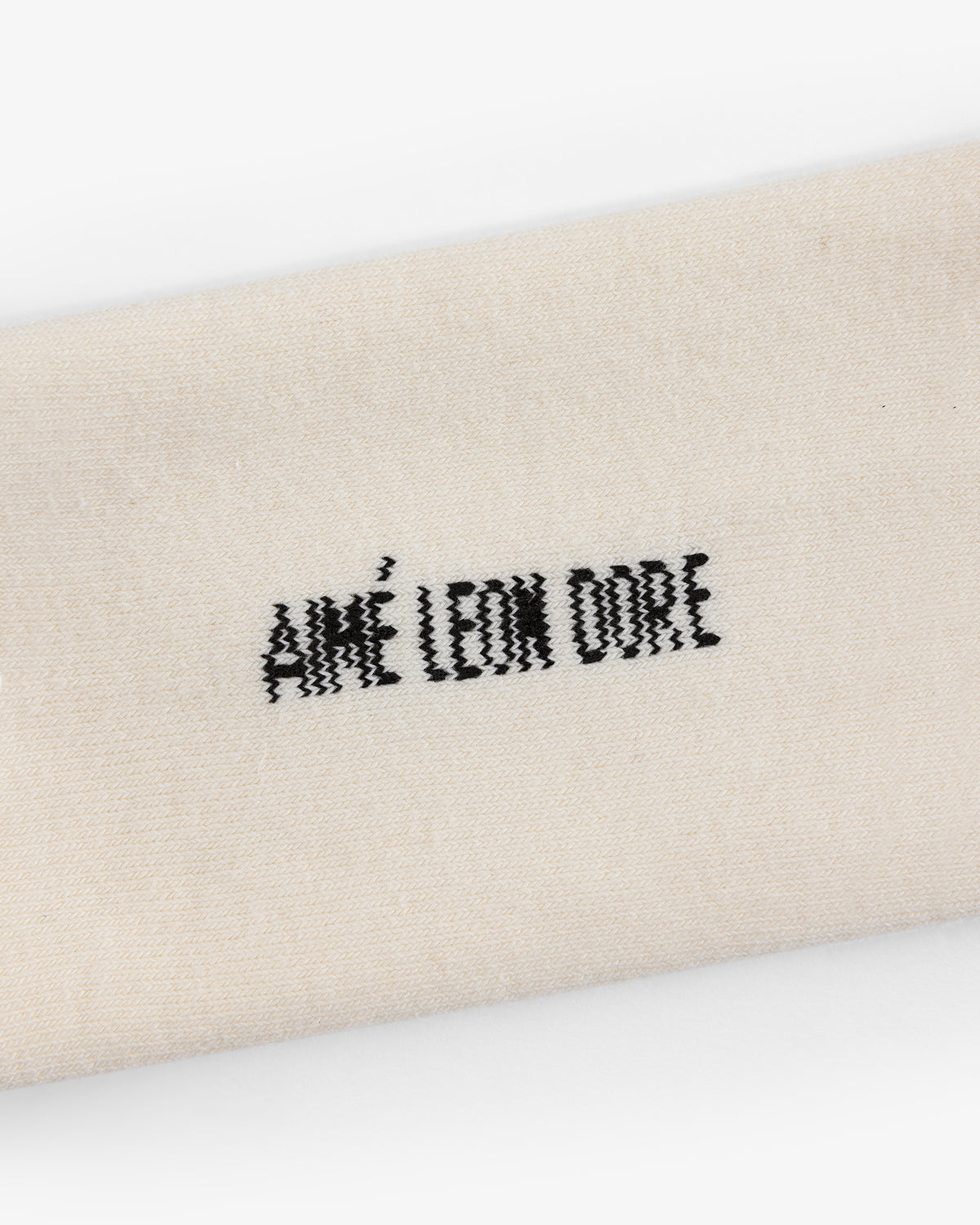 Close-up of cream-colored Crew Sock 3-Pack with AIMÉ LEON DORE embroidered in black thread.
