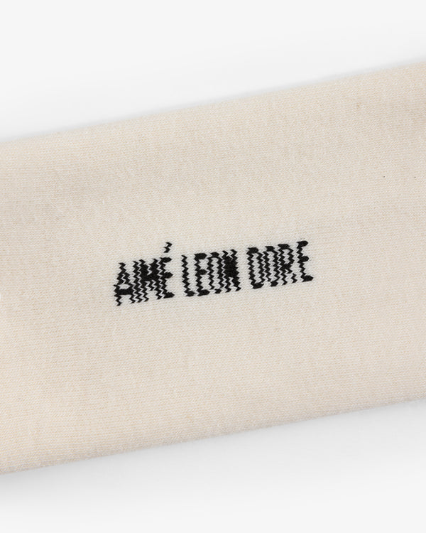 Close-up of cream-colored Crew Sock 3-Pack with AIMÉ LEON DORE embroidered in black thread.