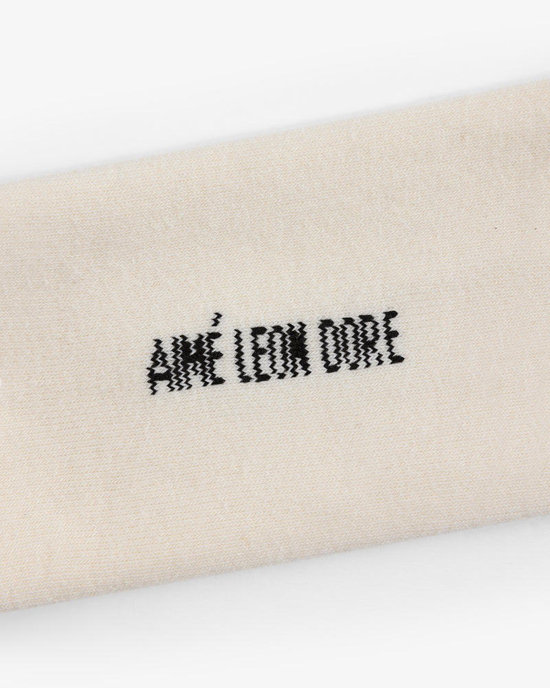 Close-up of cream-colored Crew Sock 3-Pack with AIMÉ LEON DORE embroidered in black thread.