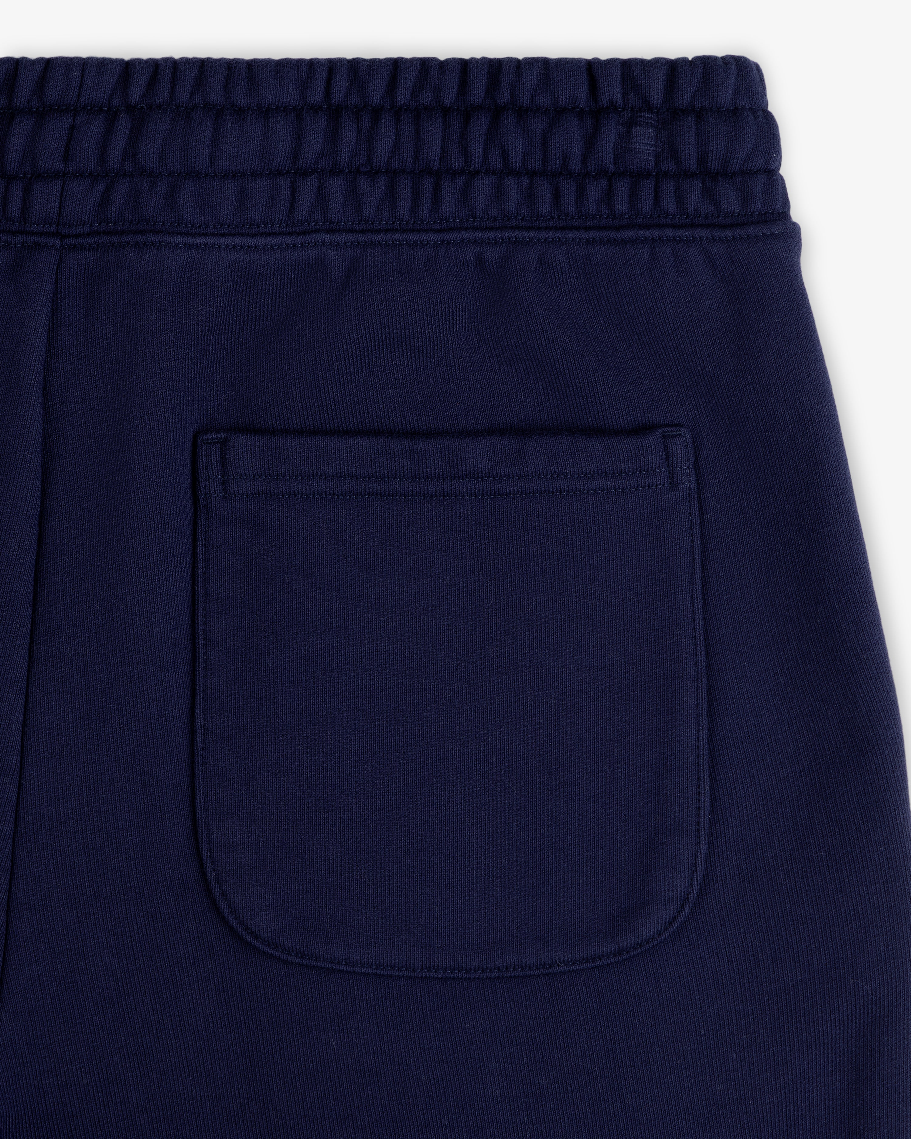 Close-up of the back pocket and elastic waistband on Unisphere Sweatpants in dark blue.