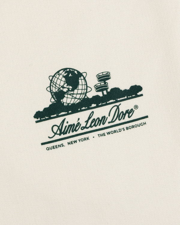 Unisphere Sweatpants feature a green Aimé Leon Dore logo and "QUEENS, NEW YORK - THE WORLDS BOROUGH" on cream fabric.