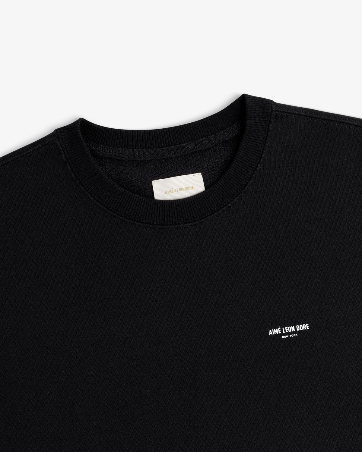 Black Micro Logo Crewneck Sweatshirt with small white AIMÉ LEON DORE text on left chest, viewed from above.