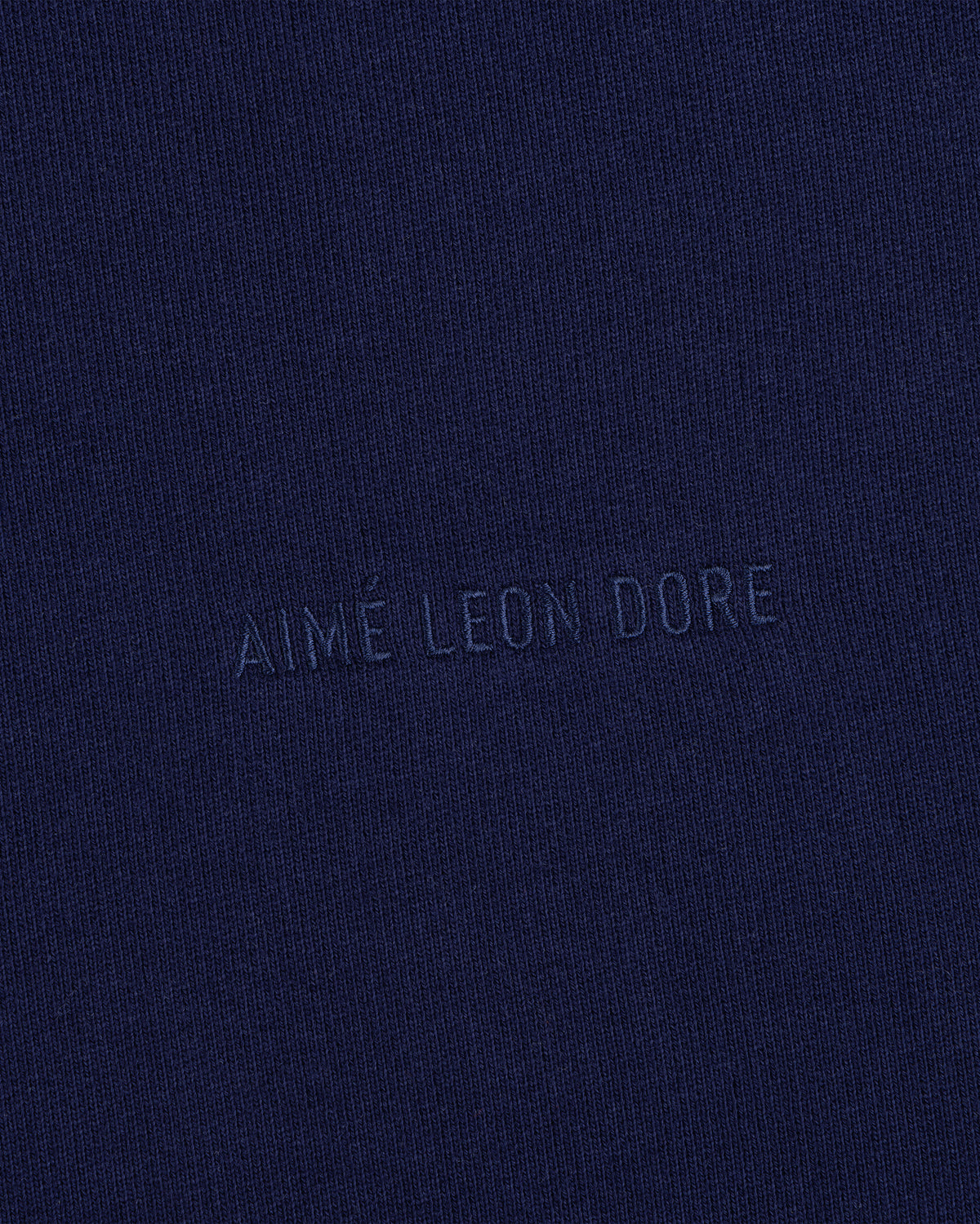 Closeup of navy fabric with Tonal Logo Crewneck Sweatshirt text subtly embossed in matching blue at the center.