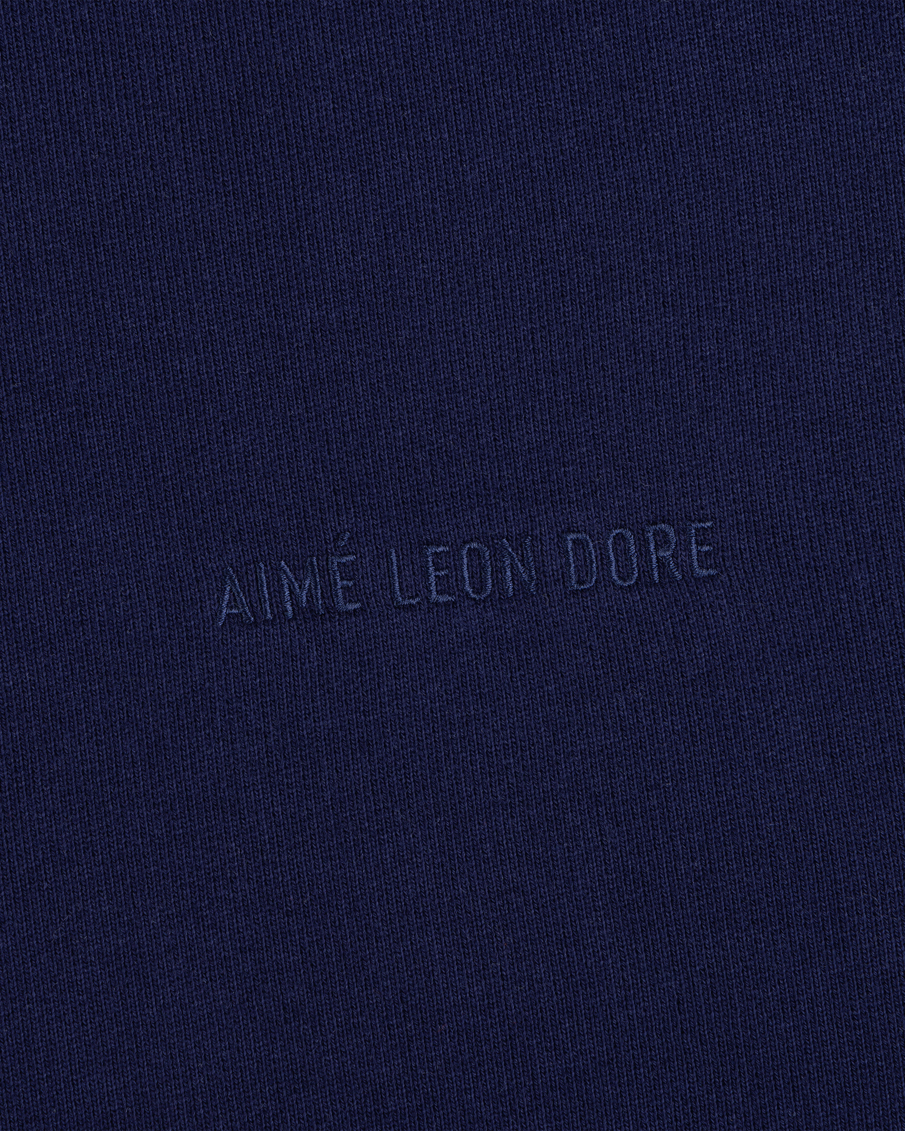 Closeup of navy fabric with Tonal Logo Crewneck Sweatshirt text subtly embossed in matching blue at the center.
