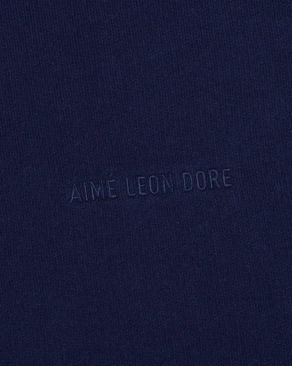 Closeup of navy fabric with Tonal Logo Crewneck Sweatshirt text subtly embossed in matching blue at the center.