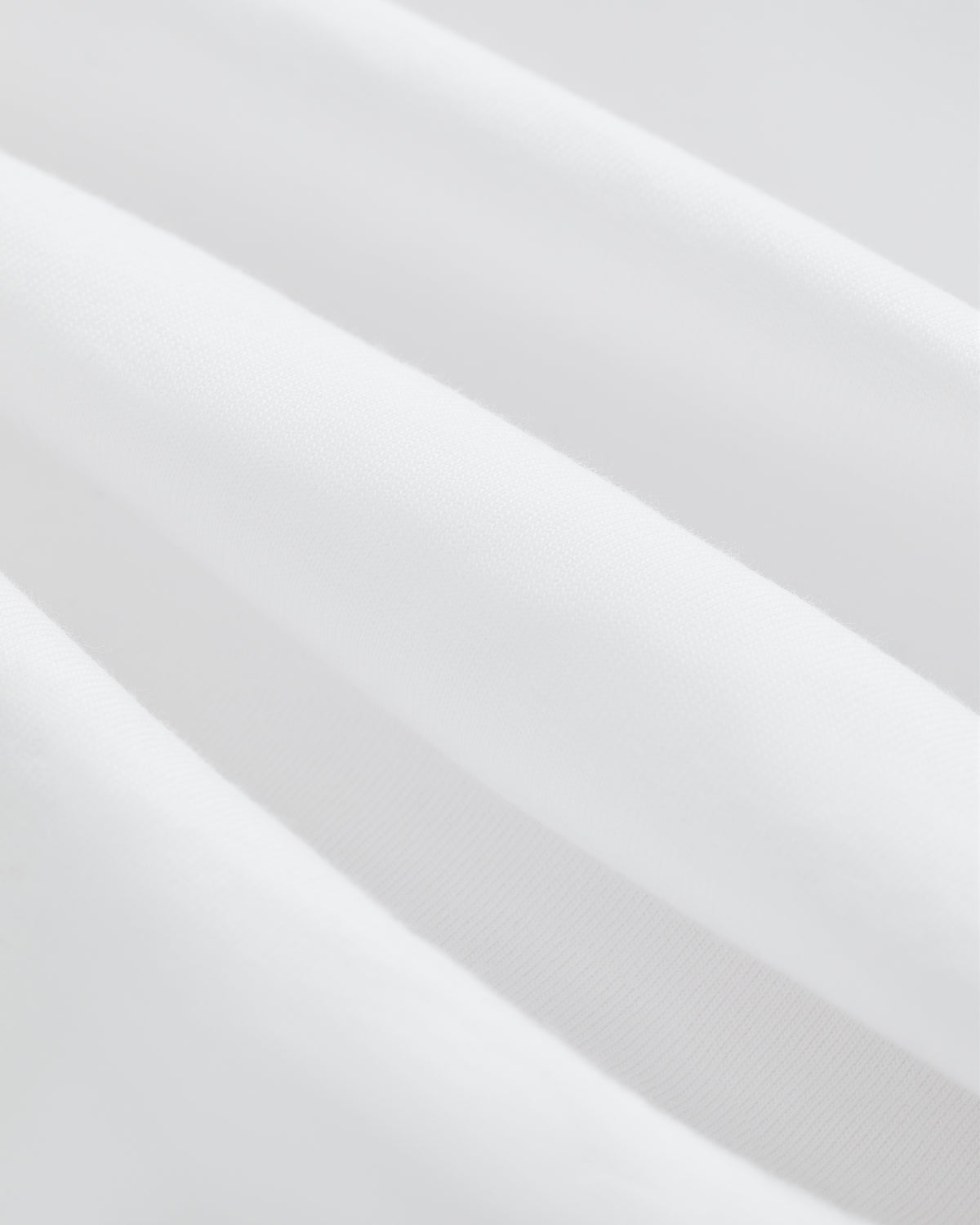 Close-up of soft, white T-Shirt 3-Pack fabric with gentle folds and smooth texture.