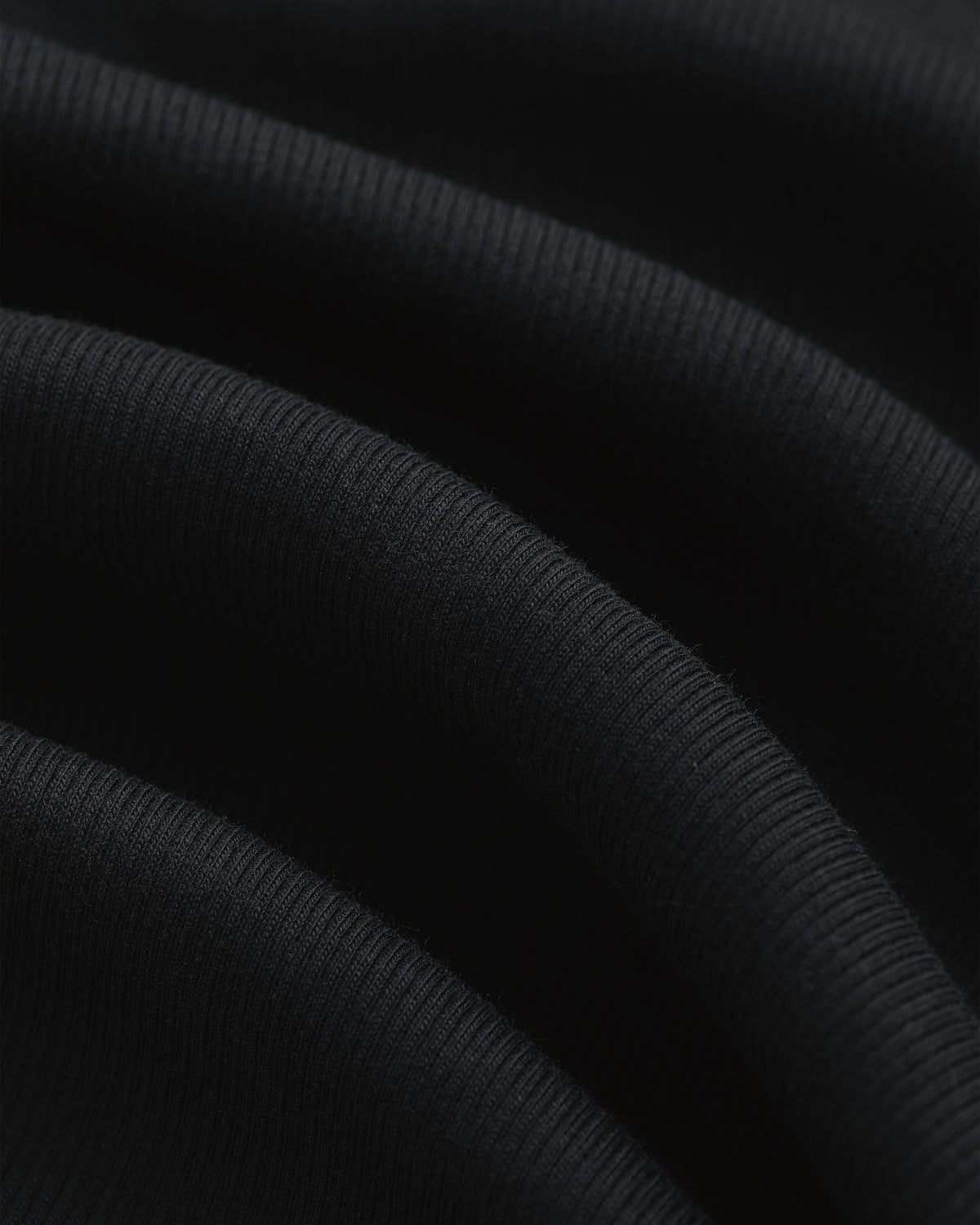 Close-up of soft, ribbed black fabric with wavy folds and texture from Tank Top 3-Pack.
